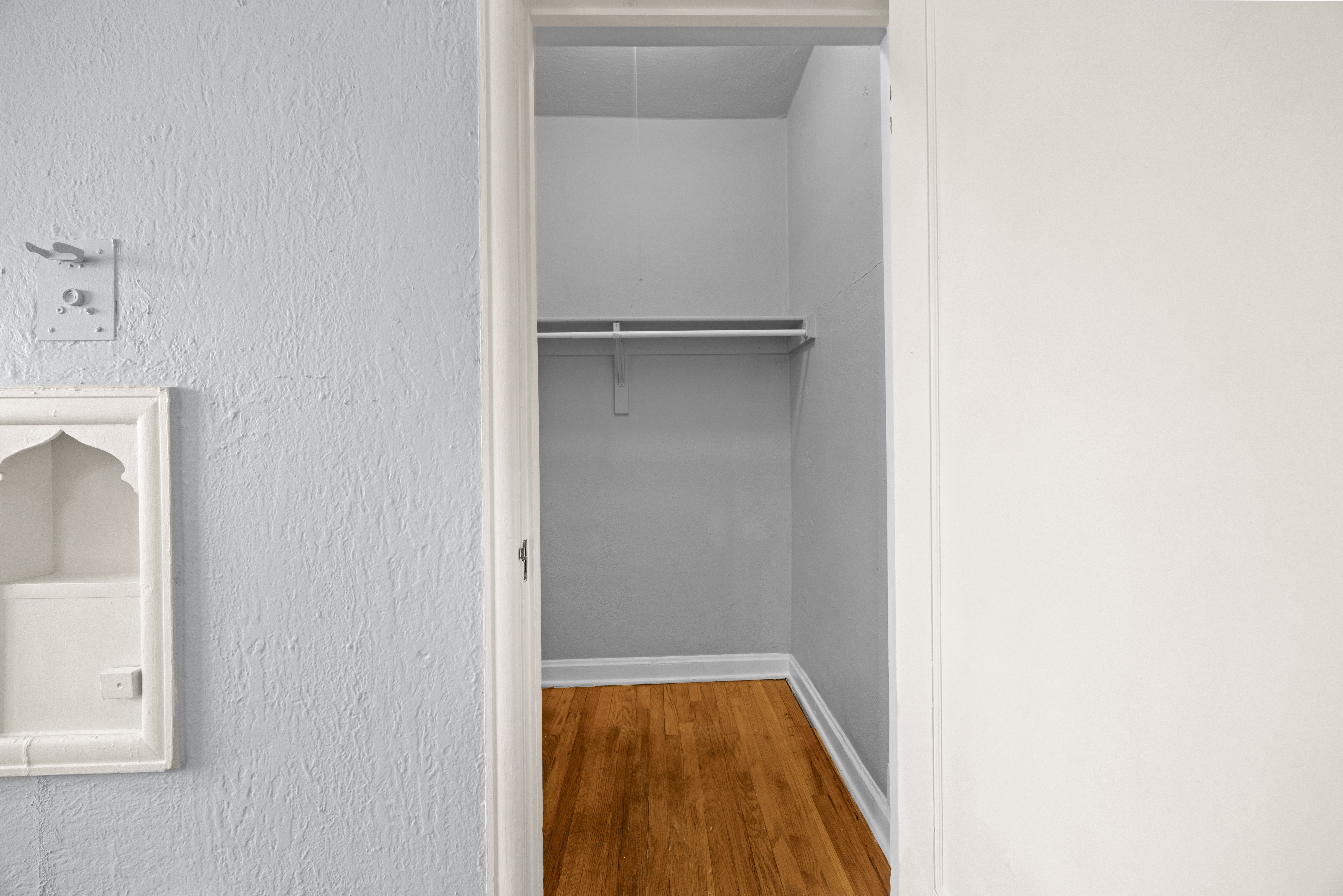 A white doorway leads to a small, empty room with a wooden floor.